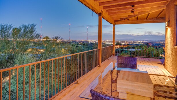 A wooden deck with a railing, a table, and chairs.