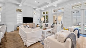 A spacious living room with white furniture, a flat-screen TV, and large windows. - WaterColor Luxury on 30A! 63 Western Lake, Park District, Pool, 7 Bdrms, Slps 16+ (Santa Rosa Beach)