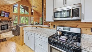 Eine moderne Küche mit Granit-Arbeitsplatten, Edelstahlgeräten und einem Kamin aus Naturstein.