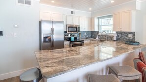 A modern kitchen with a central island, stainless steel appliances, and a large window providing natural light.