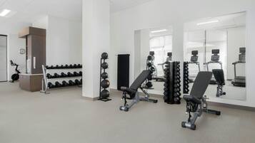 Een sportschool met trainingsapparatuur, een bank en een dumbbellsrek.