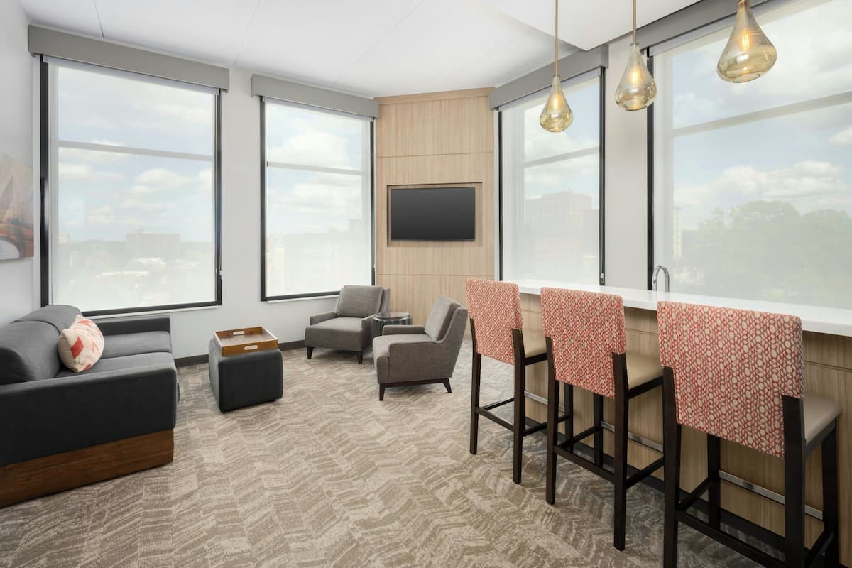 A modern living room with a sofa, armchairs, a coffee table, and a bar area with stools.