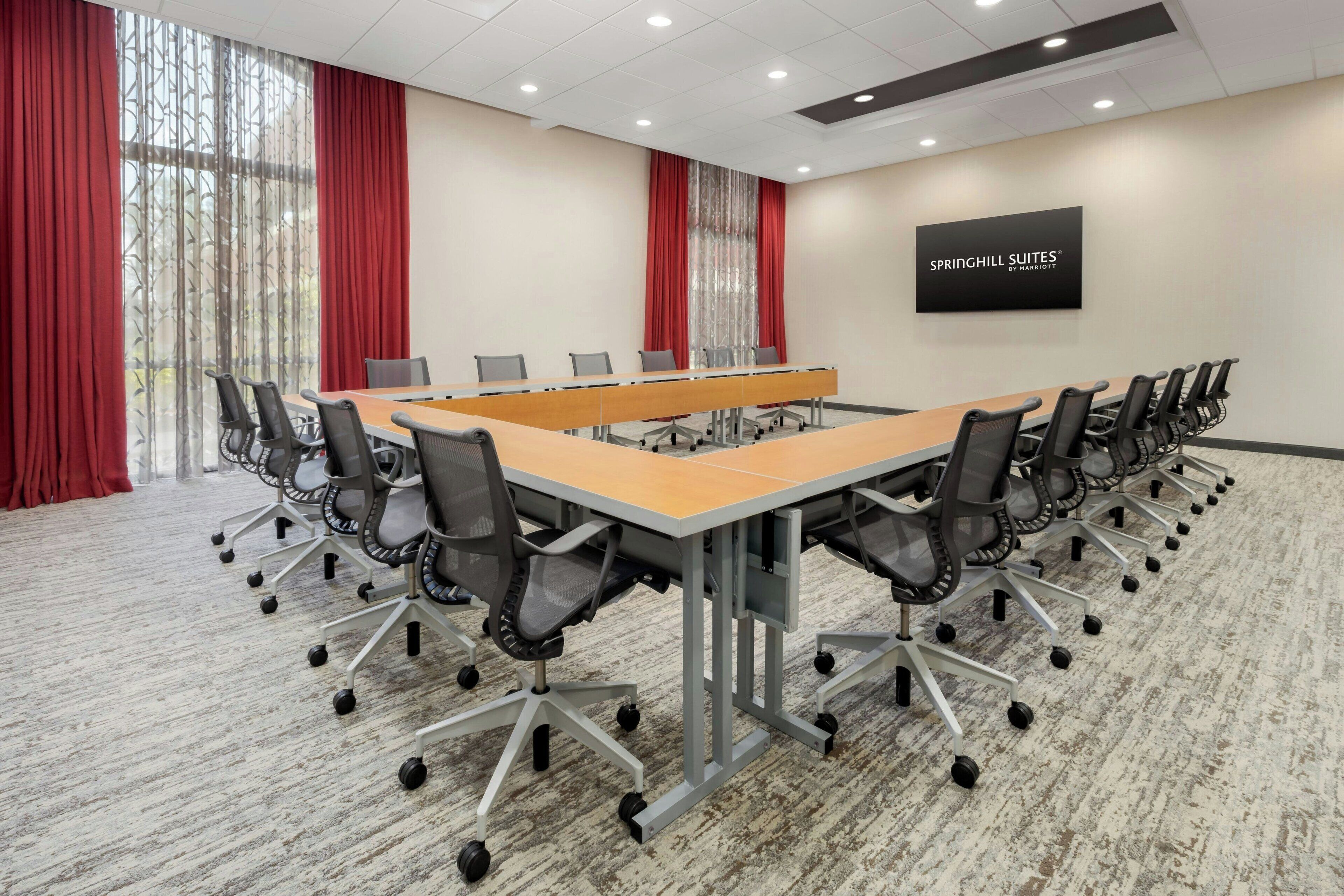 A conference room with a long table, multiple chairs, and a sign on the wall.