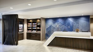 A modern reception area with a reception desk, a bookshelf, and a decorative wall with text. - SpringHill Suites by Marriott Athens Downtown/University Area (Athens)