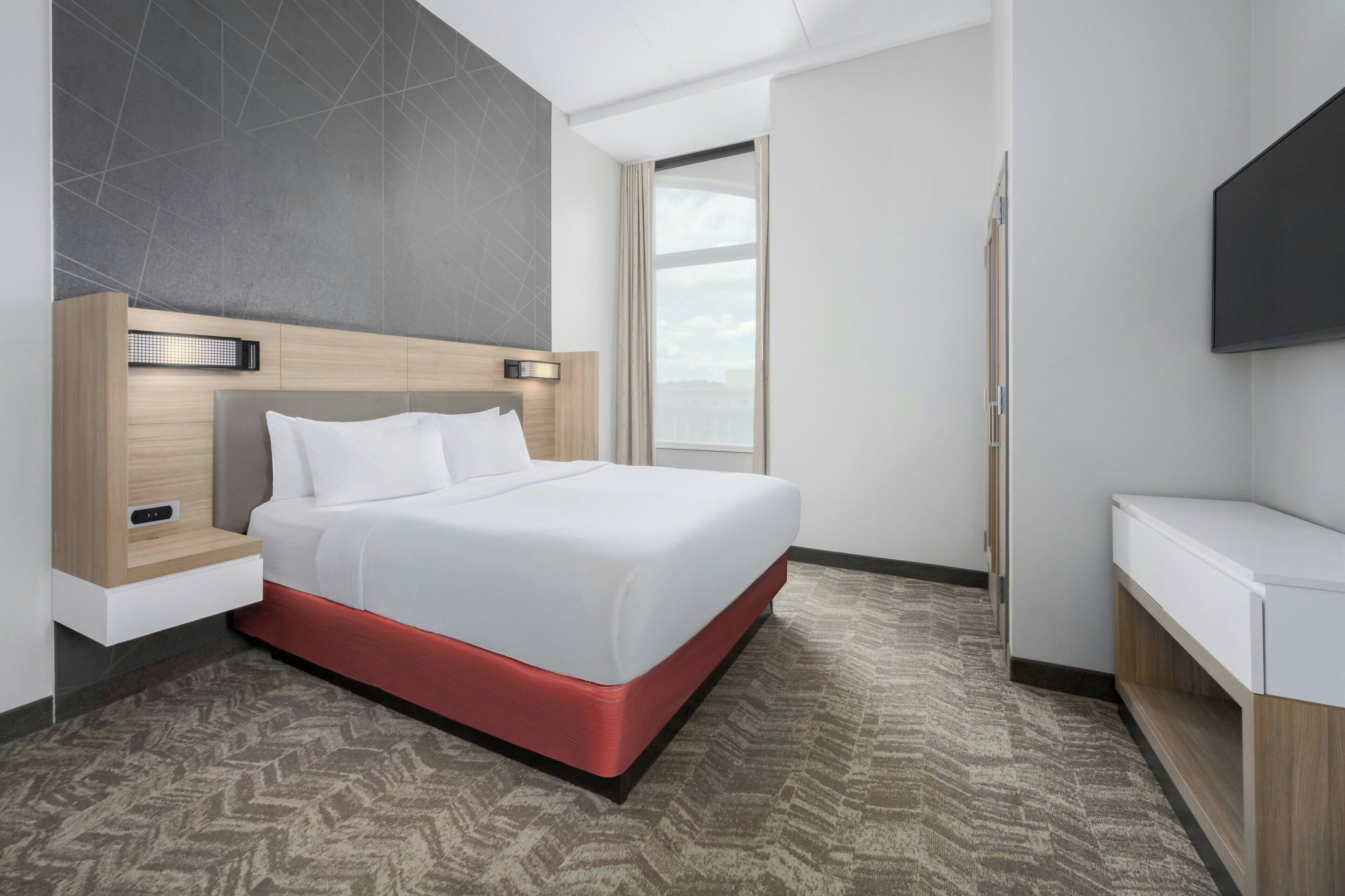Une chambre d’hôtel moderne dotée d’un grand lit, d’un chauffage intégré, d’une télévision à écran plat et offrant une vue sur l’extérieur.