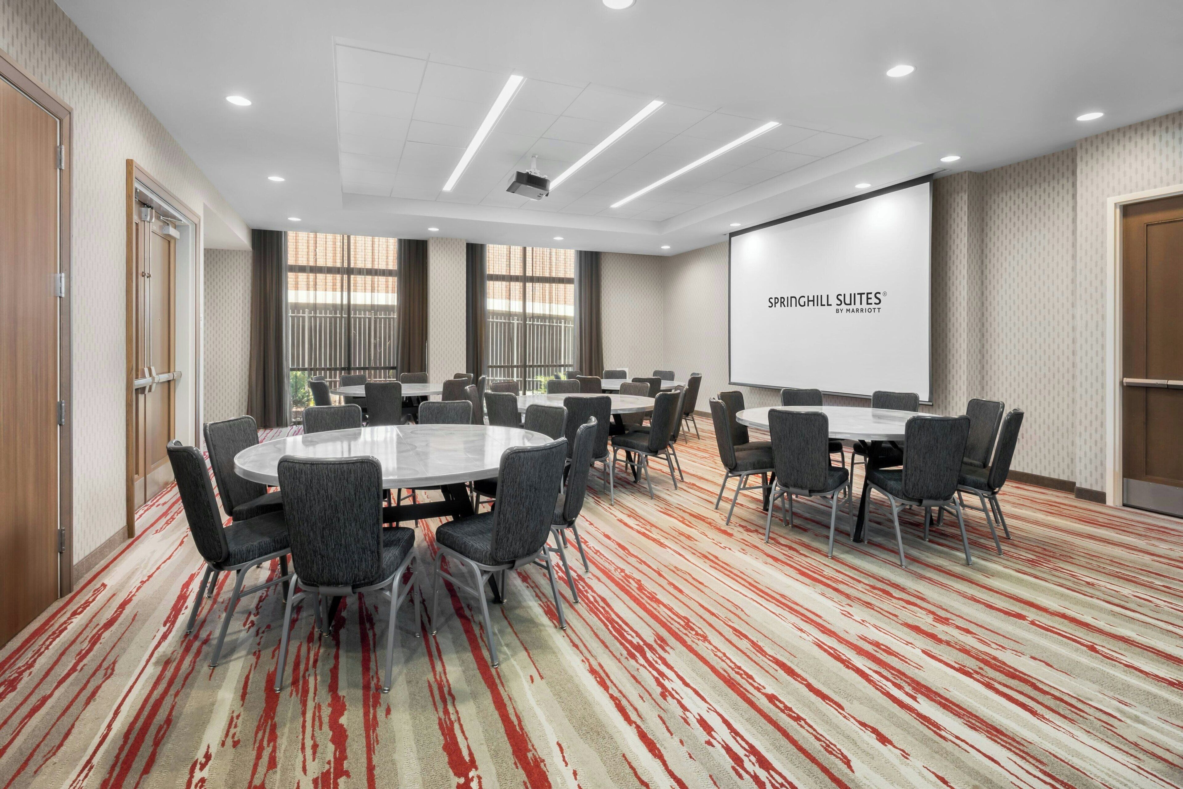 Un salón de conferencias con una pantalla grande que muestra 