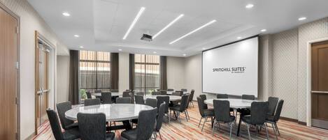 Un salón de conferencias con una pantalla grande que muestra