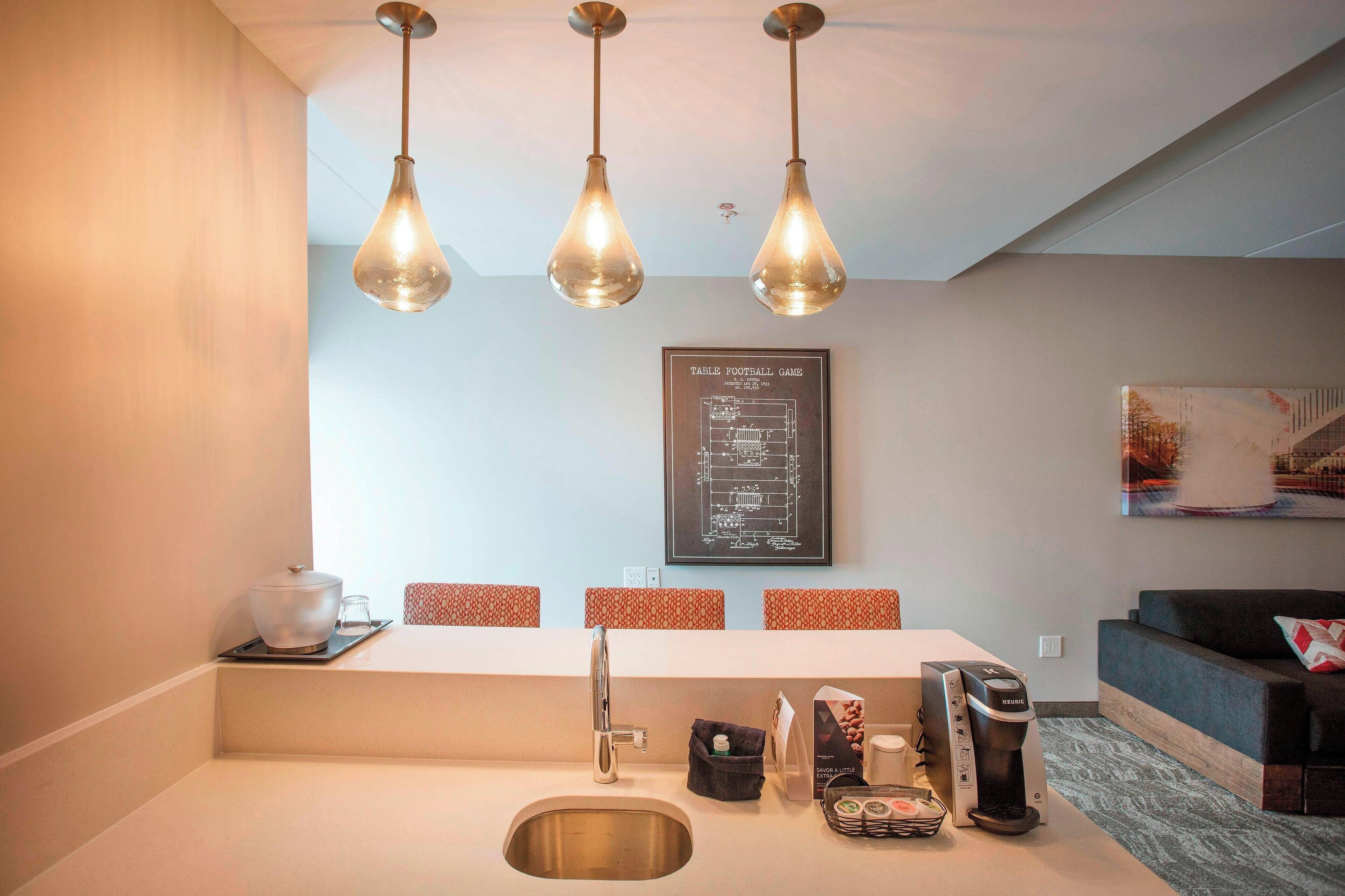 Une cuisine moderne équipée d’un évier, d’une machine à café et d’un plan architectural encadré accroché au mur.