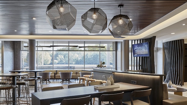 A modern dining area with hexagonal pendant lights, a large window with a view, and a flat-screen TV on the wall. - SpringHill Suites by Marriott Athens Downtown/University Area (Athens)