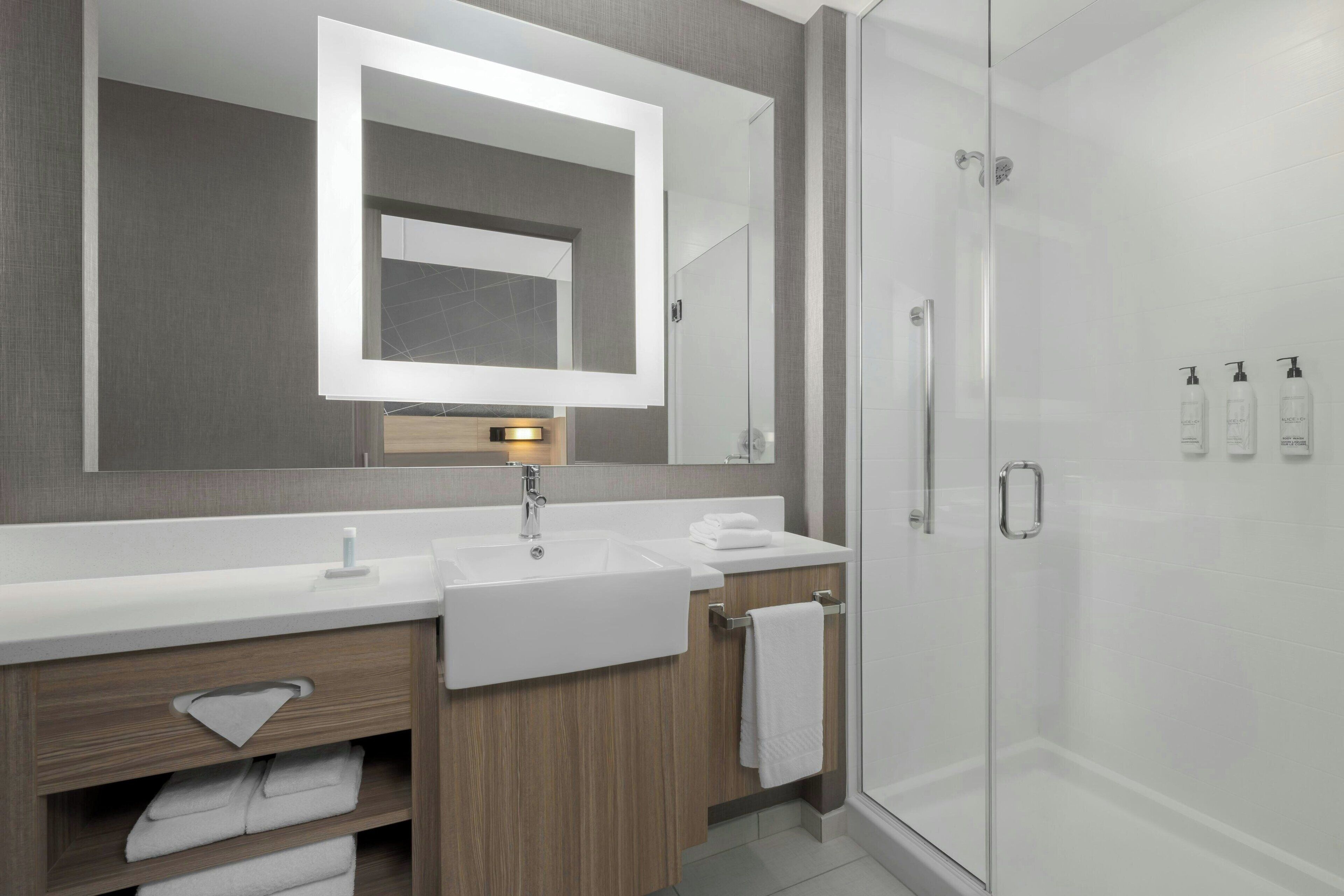 Une salle de bain moderne avec deux lavabos, un grand miroir et une douche à l’italienne.