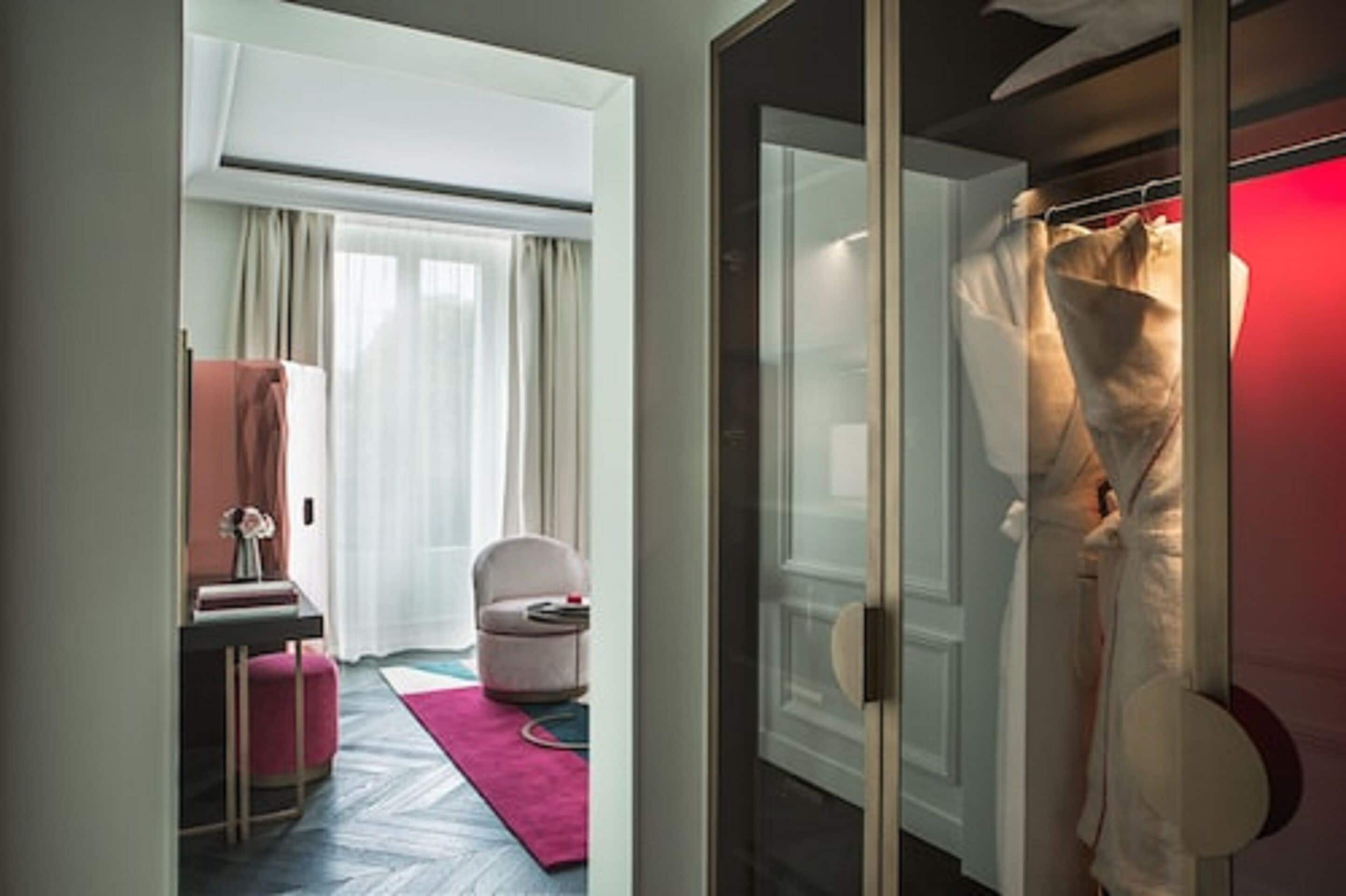Une chambre d’hôtel avec un lit, un bureau, une chaise et un peignoir suspendu à un porte-manteau.