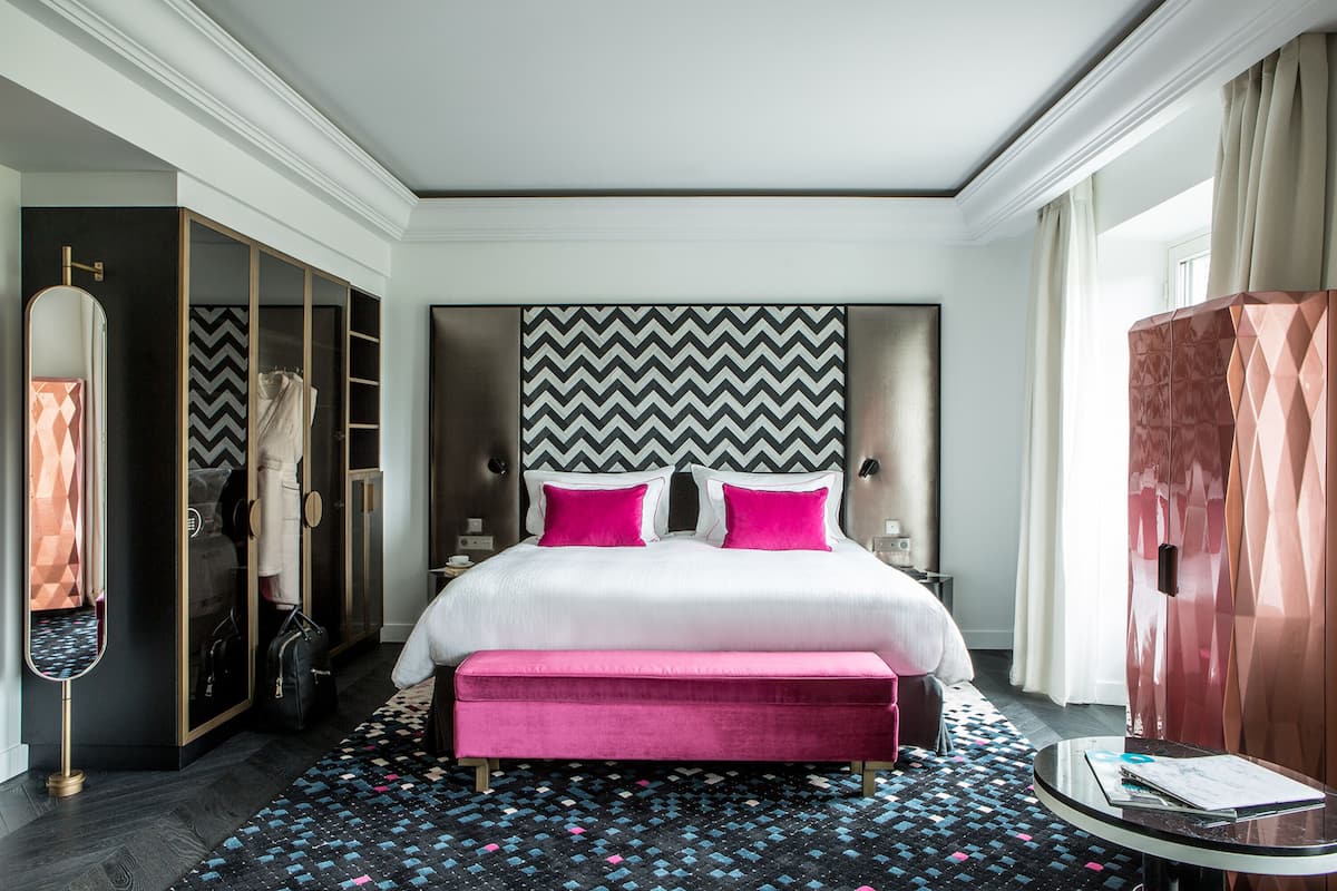 A hotel room with a large bed, a walk-in closet, and a patterned rug.