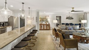 Et moderne køkken med en bar, et spisebord og en opholdsstue med sofa og stole.