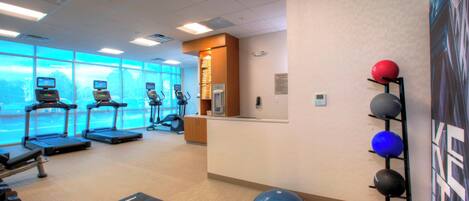 Un gimnasio con cintas de correr, pelotas de ejercicio y un amplio ventanal con vistas.
