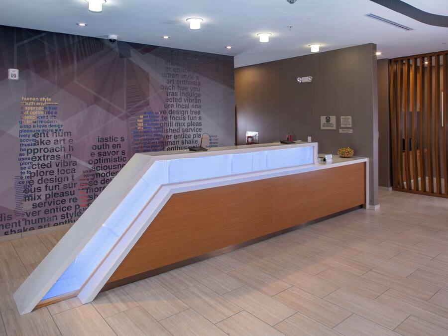 A reception desk with a modern design, a wall with text, and a wooden partition.