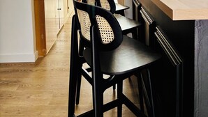 A modern kitchen with a wooden countertop, black chairs, and a view of a balcony. - Hôtel Bonaparte (Bastia)