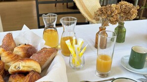 A breakfast setting with pastries, juice, and a green mug on a table. - Hôtel Bonaparte (Bastia)