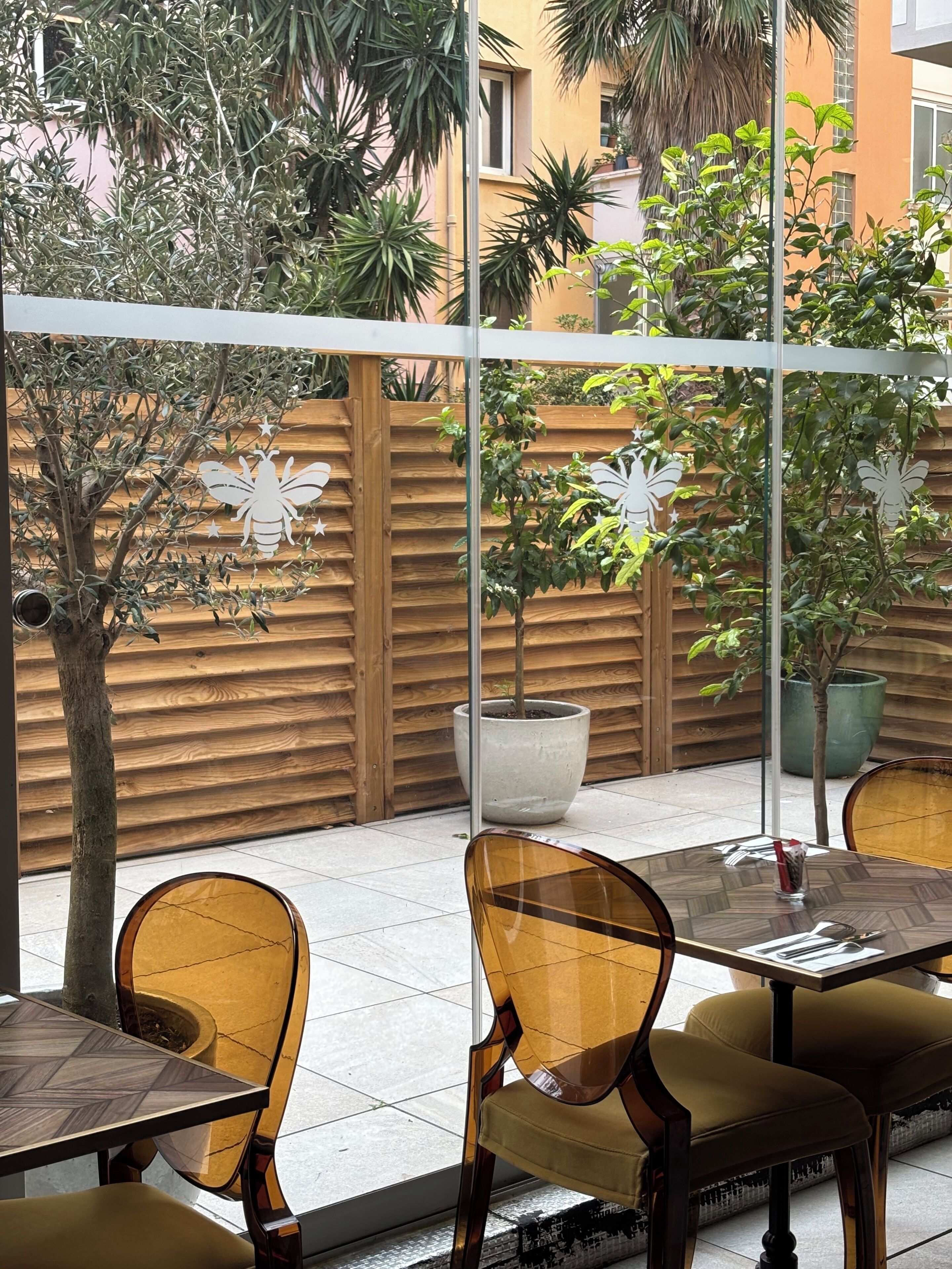 Une terrasse avec des meubles en bois, une table en verre et des plantes en pot.