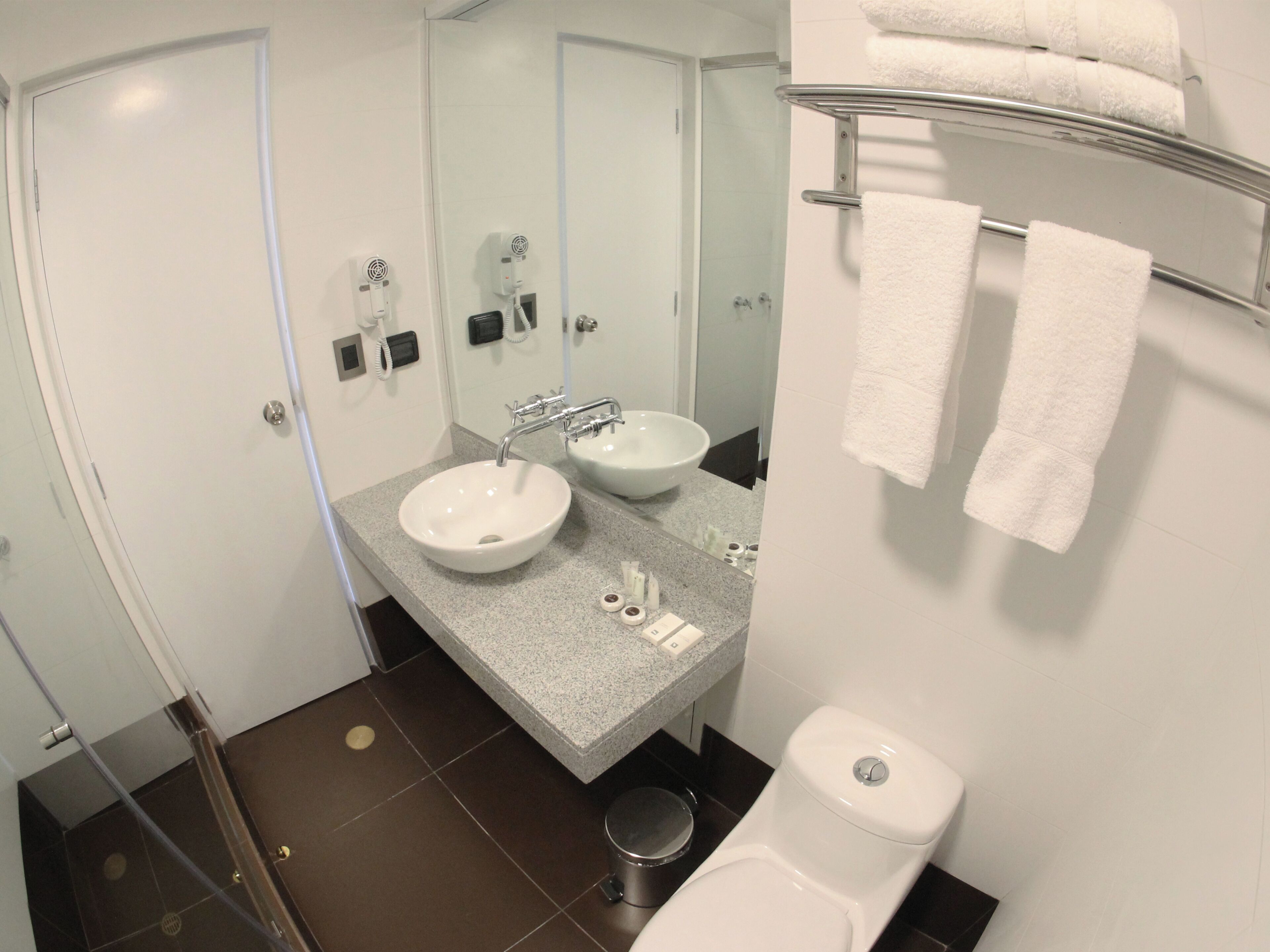 A bathroom with two sinks, a toilet, a shower, and a mirror.