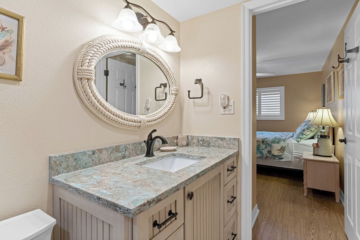 A bathroom with a round mirror, a sink, and a vanity with drawers. There is a towel rack and a light fixture above the mirror.