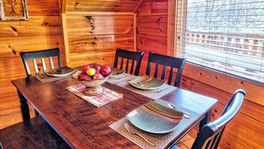 Una mesa de madera con individuales, platos y un cuenco de fruta.