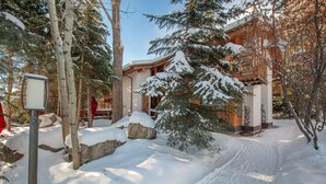 A snow-covered building with a wooden facade, surrounded by trees and rocks.