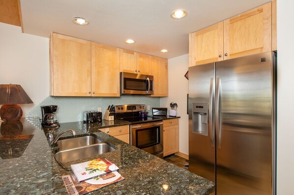 A modern kitchen with granite countertops, stainless steel appliances, and wooden cabinets.