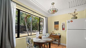 Comedor con mesa, sillas, refrigerador y ventana con cortinas.