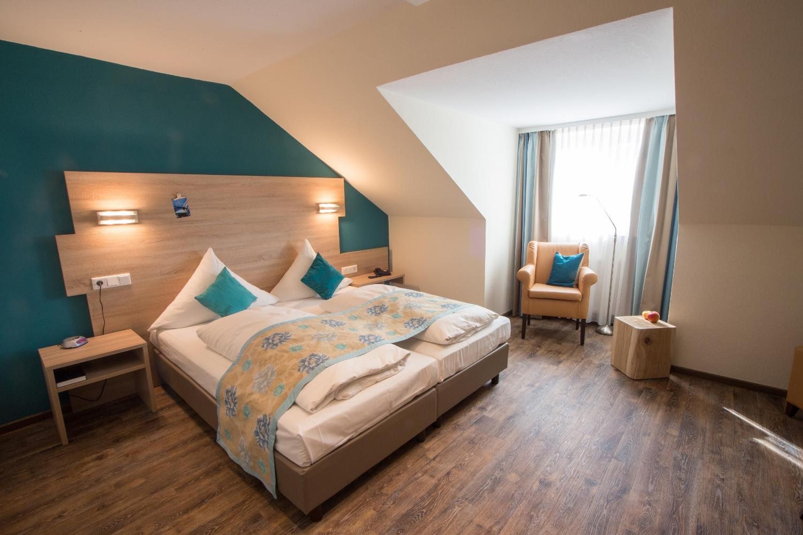 A bedroom with a large bed, a nightstand, a chair, and a small table.