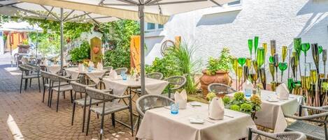 An outdoor café with tables and chairs, umbrellas, and decorative glassware.