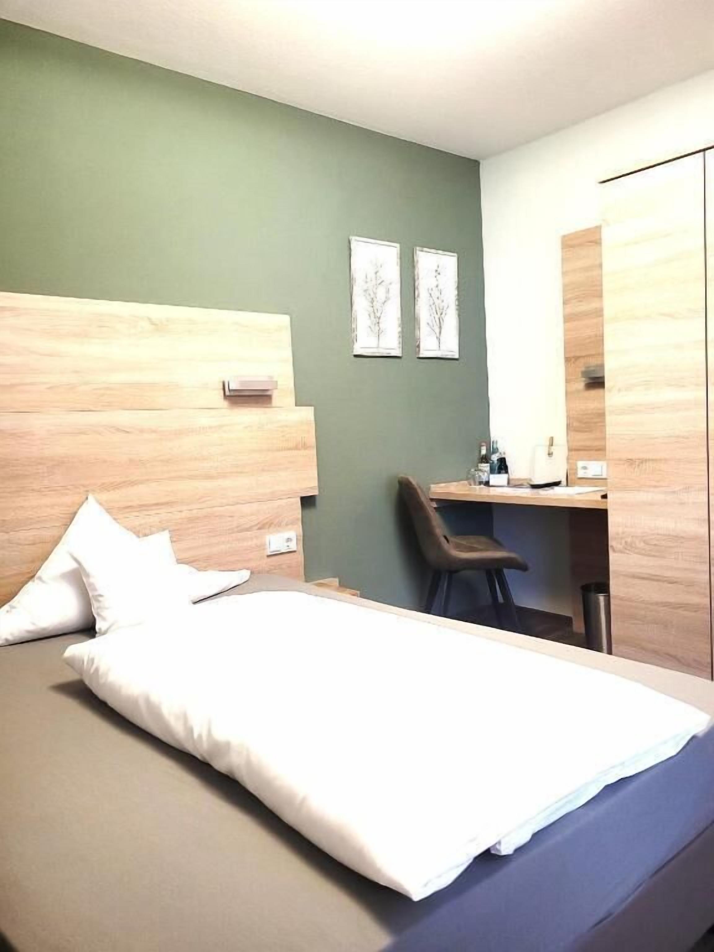 Una habitación de hotel con cama, escritorio, silla y espejo.