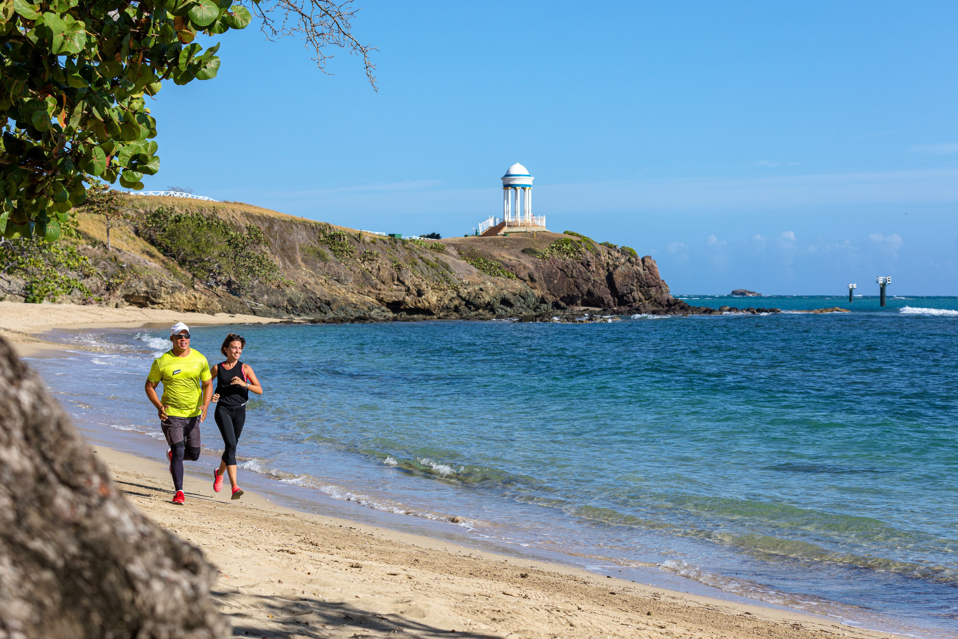 Una playa con un faro al fondo.