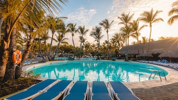 Alberca al aire libre, sombrillas en la alberca y camastros