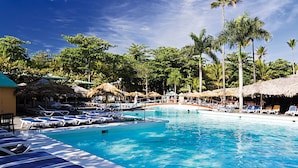 A swimming pool with lounge chairs and palm trees.