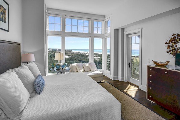 Un dormitorio con una cama grande, un aparador y vistas al océano.