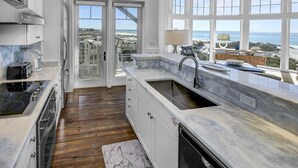 A modern kitchen with a large island, a view of the ocean, and a balcony with a view of the beach. - Gulf Front Penthouse Condo * Complimentary LSV 407 Compass Point 1, WaterSound - 3 BR, SLPS 8 (Panama City Beach)