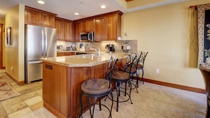 A kitchen with wooden cabinets, stainless steel appliances, and a central island with bar stools.