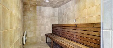 Eine Sauna mit Kacheln, einer Holzbank und einem Lüftungssystem.