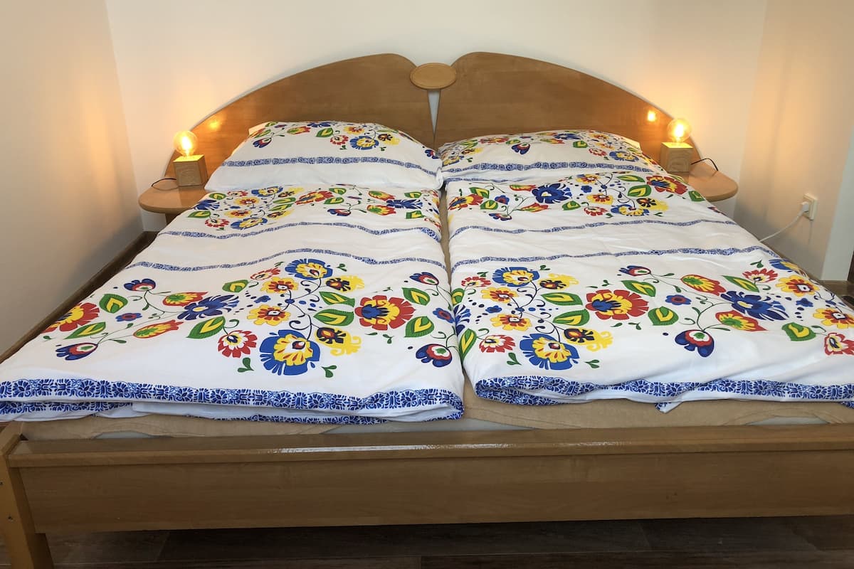 A bed with a floral bedspread, wooden headboard, and bedside lamps.