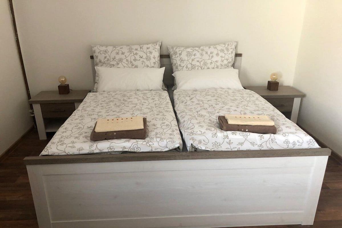 A double bed with floral-patterned bedding, two bedside tables with lamps, and a wooden floor.