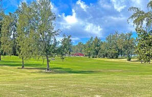 Un campo de golf con un edificio rojo identificado como 'The Stars' a lo lejos.