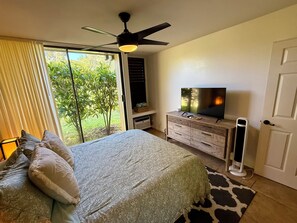 Un dormitorio con cama, televisor, cómoda y ventilador de techo.