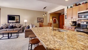 Una cocina moderna con encimeras de granito, electrodomésticos de acero inoxidable y armarios de madera.