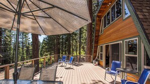 Une terrasse en bois avec des meubles d’extérieur, une table et un parasol.