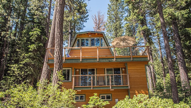 Une cabane dotée d’un balcon, entourée d’arbres.