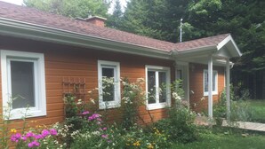 A wooden house with three windows and a covered porch. - Beautiful lakefront cottage, 1 hour north of Montreal (Wentworth)