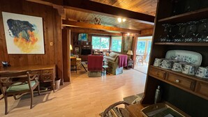 A cozy cabin interior with a wooden dining table, chairs, a sofa, and a fireplace. - Beautiful lakefront cottage, 1 hour north of Montreal (Wentworth)