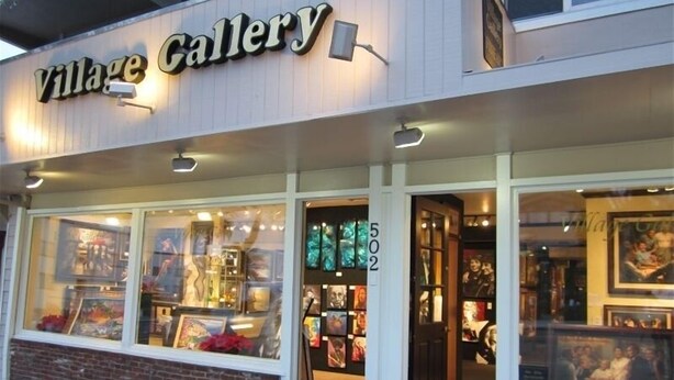 L’extérieur de la galerie Village Gallery se distingue par ses grandes vitrines et son socle en briques.