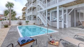 Une piscine avec une terrasse en bois, des chaises longues et une bouteille de vin.