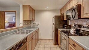 A modern kitchen with wooden cabinets, stainless steel appliances, and a grey countertop. - Vs643s Village Square Condo (Copper Mountain)